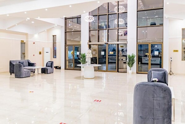 A spacious lobby with seating areas, a reception desk, and large windows.