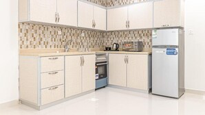 Una cucina con rivestimento piastrellato, forno a incasso, frigorifero e macchina da caffè.