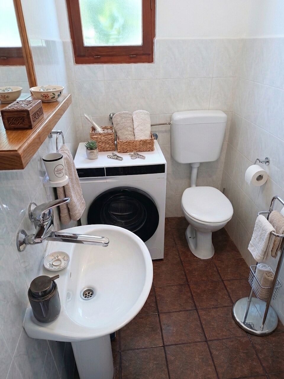A compact bathroom with a sink, toilet, and washing machine.