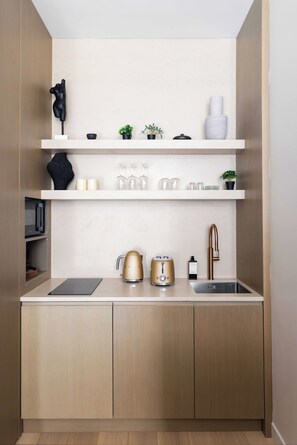A modern kitchen with wooden cabinets, a sink, a countertop, and various kitchen items. - Luxurious Suite A/C - 2P - Madeleine/saint-honore (Paris)