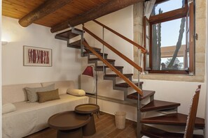 A staircase with wooden steps and metal railings, a sofa with cushions, a small round table, and a radiator. - Casa Dell' Aristea, a Private Venetian Manor (Rethymno)