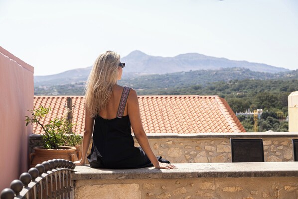 A person sitting on a stone ledge overlooking a mountainous landscape. - Casa Dell' Aristea, a Private Venetian Manor (Rethymno)