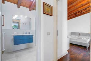 A modern bathroom with a blue vanity, a mirror, and a framed picture on the wall. - Paul Spacious Central Apart & Garage (Salò)