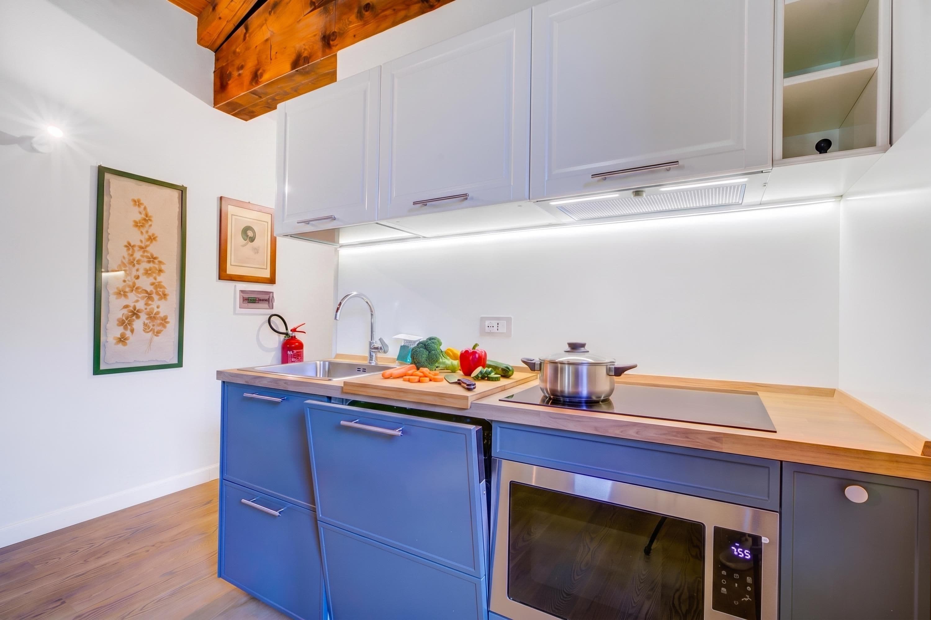 A modern kitchen with a built-in dishwasher, oven, and a wooden countertop.