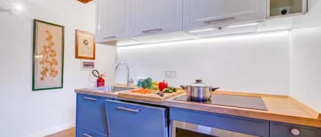 Une cuisine moderne équipée d’un lave-vaisselle et d’un four intégrés, ainsi que d’un plan de travail en bois.