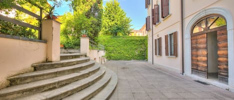 A stone staircase leading up to a building with a white facade and brown shutters.