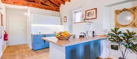 Eine moderne Küche mit einer zentralen Kochinsel, Holzbalken an der Decke und einem Feuerlöscher an der Wand.