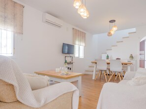 Ein modernes Wohnzimmer mit einer Couch, einem Esstisch und einem Fernseher.