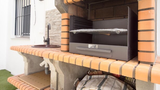 An outdoor brick oven grill with a chimney, a window with bars, and a small outdoor sink. - las Torres 215 in Chiclana de la Frontera (Chiclana de la Frontera)