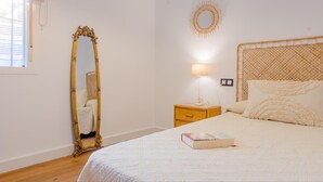 A bedroom with a bed, a bedside table, a lamp, a mirror, and a wall decoration. - las Torres 215 in Chiclana de la Frontera (Chiclana de la Frontera)