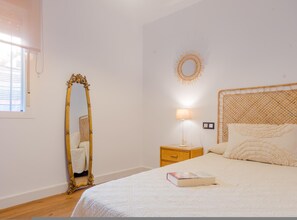 Ein Schlafzimmer mit einem Bett, einem Nachttisch, einer Lampe, einem Spiegel und einer Wanddekoration.