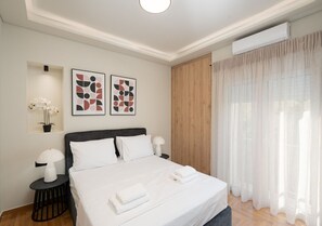 Ein modernes Hotelzimmer mit einem Bett, zwei Nachttischlampen, einer Wand-Klimaanlage und abstrakter Kunst.
