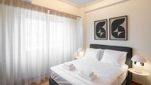 Ett hotellrum med en säng, två sänglampor och två abstrakta konstverk på väggen.