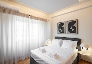 A hotel room with a bed, two bedside lamps, and two abstract wall art pieces. - LIV - Chic 2BR Signature Flat | Near Metro (Athens)