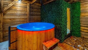Ein Holzblock-Innenraum mit Whirlpool, Holzwänden und einer grünen Wandgestaltung.