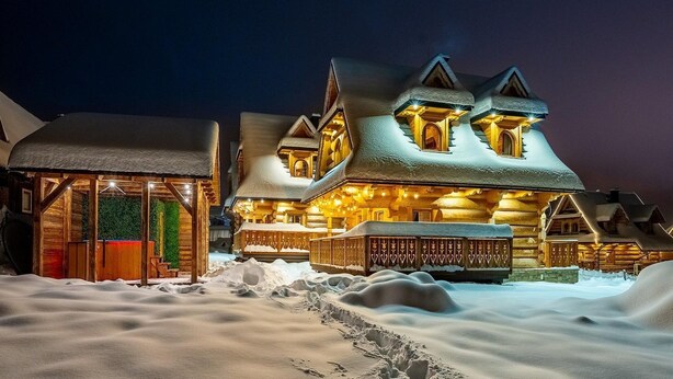 Eine schneebedeckte Lodge mit markantem Eingang und zahlreichen Fenstern, eingebettet in eine verschneite Landschaft.