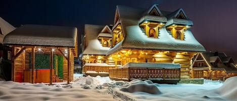 A snow-covered lodge with a prominent entrance and multiple windows, surrounded by a snowy landscape.