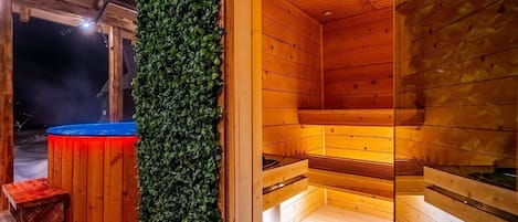 A sauna with wooden walls and benches, a blue hot tub, and a green wall.
