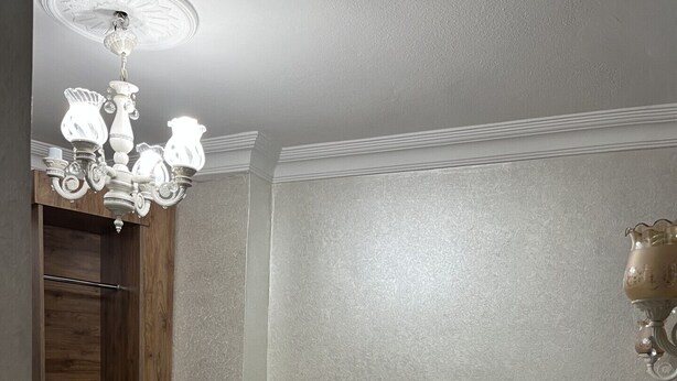 A hotel room with a bed, a radiator, a towel, a wooden wardrobe, and a chandelier. - New Room Hotel (İstanbul)