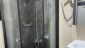 A bathroom with a glass-enclosed shower, a toilet, and a sink. - New Room Hotel (İstanbul)