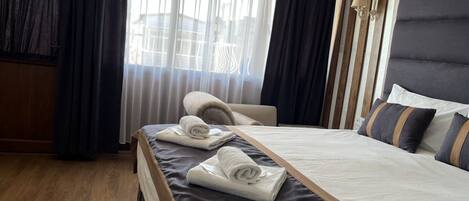 Une chambre d’hôtel avec un lit, une chaise et une fenêtre avec des rideaux.