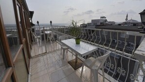 A balcony with a table and chairs, a potted plant, and a view of the cityscape. - New Room Hotel (İstanbul)