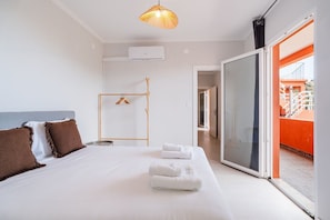 Ein Hotelzimmer mit Bett, einer Pendelleuchte, einer Schiebetür zu einem Außenbereich und einer sichtbaren Klimaanlage.