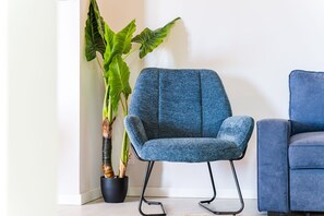 A room with a blue armchair, a potted plant, and a white wall. - GuestReady - Casa da Vereda (Arco da Calheta)