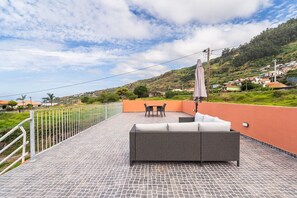 Eine Dachterrasse mit Korbmöbeln, einem Tisch und einem Sonnenschirm.
