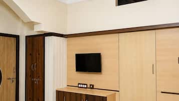 A modern room with a flat-screen TV mounted on the wall, wooden cabinets, and a door with a circular handle.
