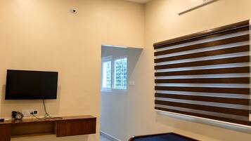 Una sala de estar moderna con ventilador de techo, televisor de pantalla plana, banco de madera y sofá con persianas horizontales.