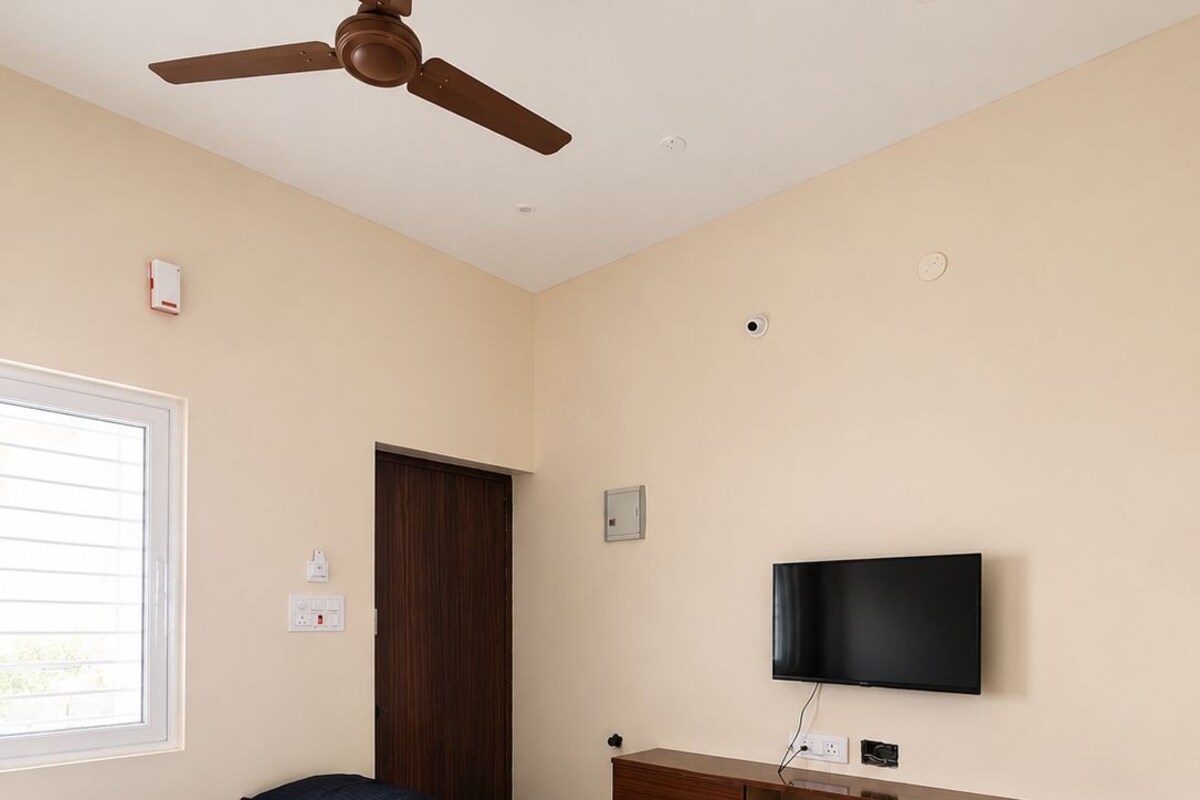 Un dormitorio con cama, ventilador de techo, televisor y armario.