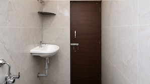 A bathroom with a shower, sink, and a dark wooden door.