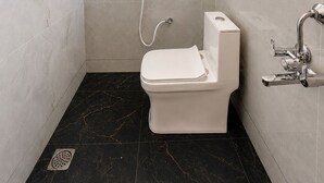 A compact bathroom with a toilet, shower, and a handrail.