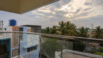 A balcony with a view of a residential area, including buildings and palm trees.