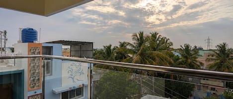 A balcony with a view of a residential area, including buildings and palm trees.