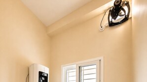 A compact kitchen with a coffee maker, a black refrigerator, and a window with blinds.