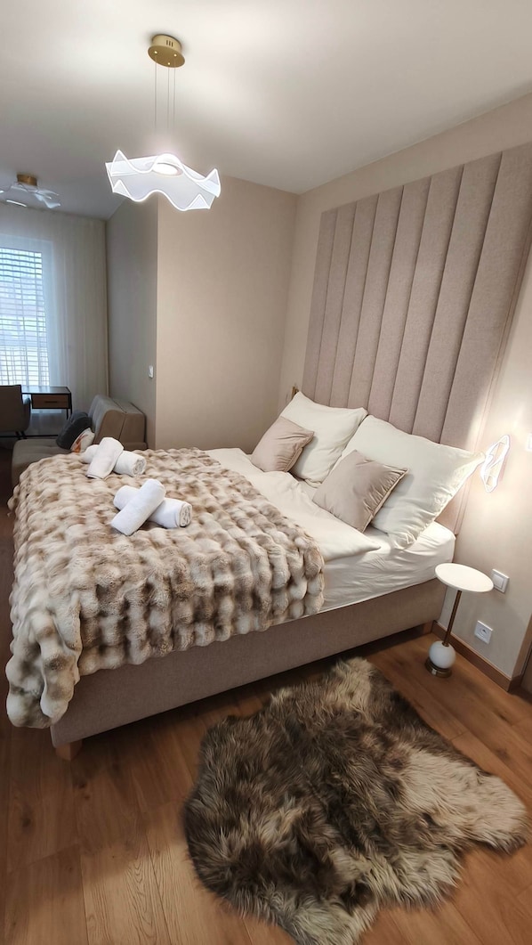 Un dormitorio con una cama, una alfombra de piel, un escritorio y una silla.