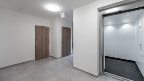 Ein Flur mit zwei Holztüren und einem modernen Aufzug.