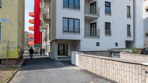 Ein mehrstöckiges Wohngebäude mit Balkonen, blauem Himmel und einem gepflasterten Gehweg.