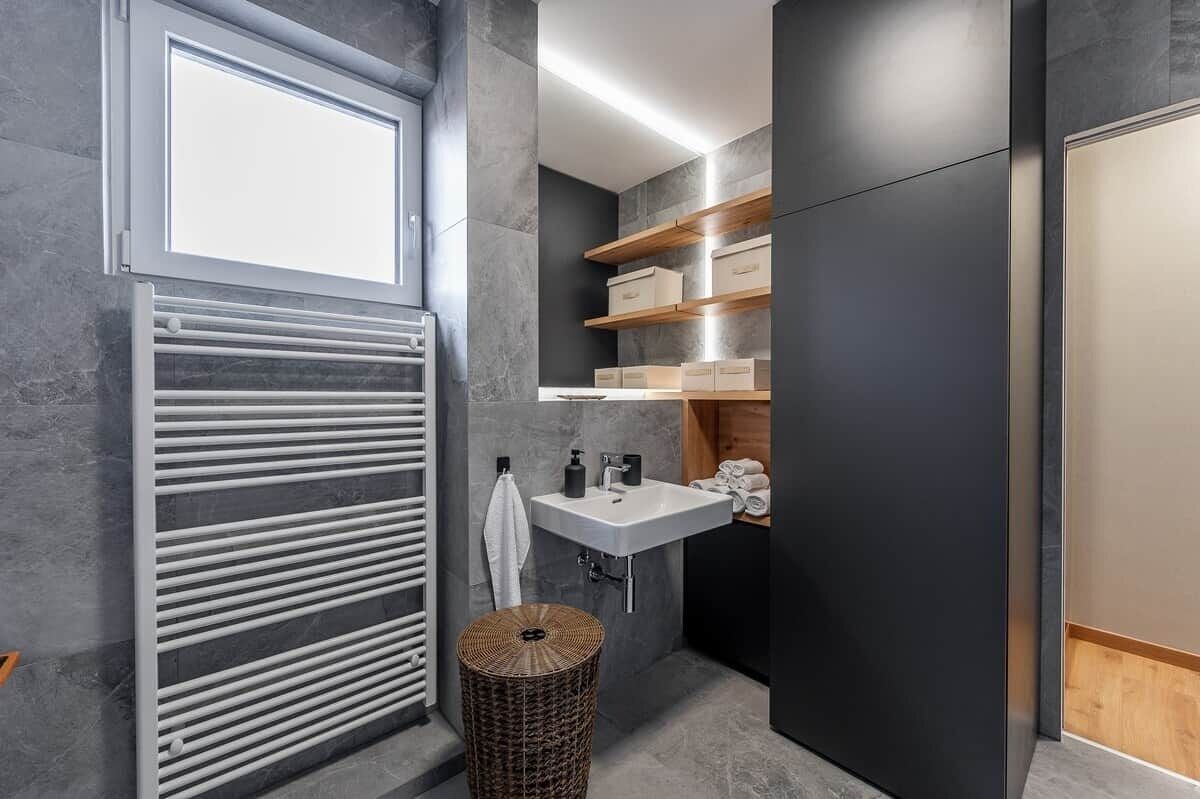 Ein modernes Badezimmer mit integriertem Waschbecken, einem Handtuchhalter und einer Holzeinrichtungsregal.