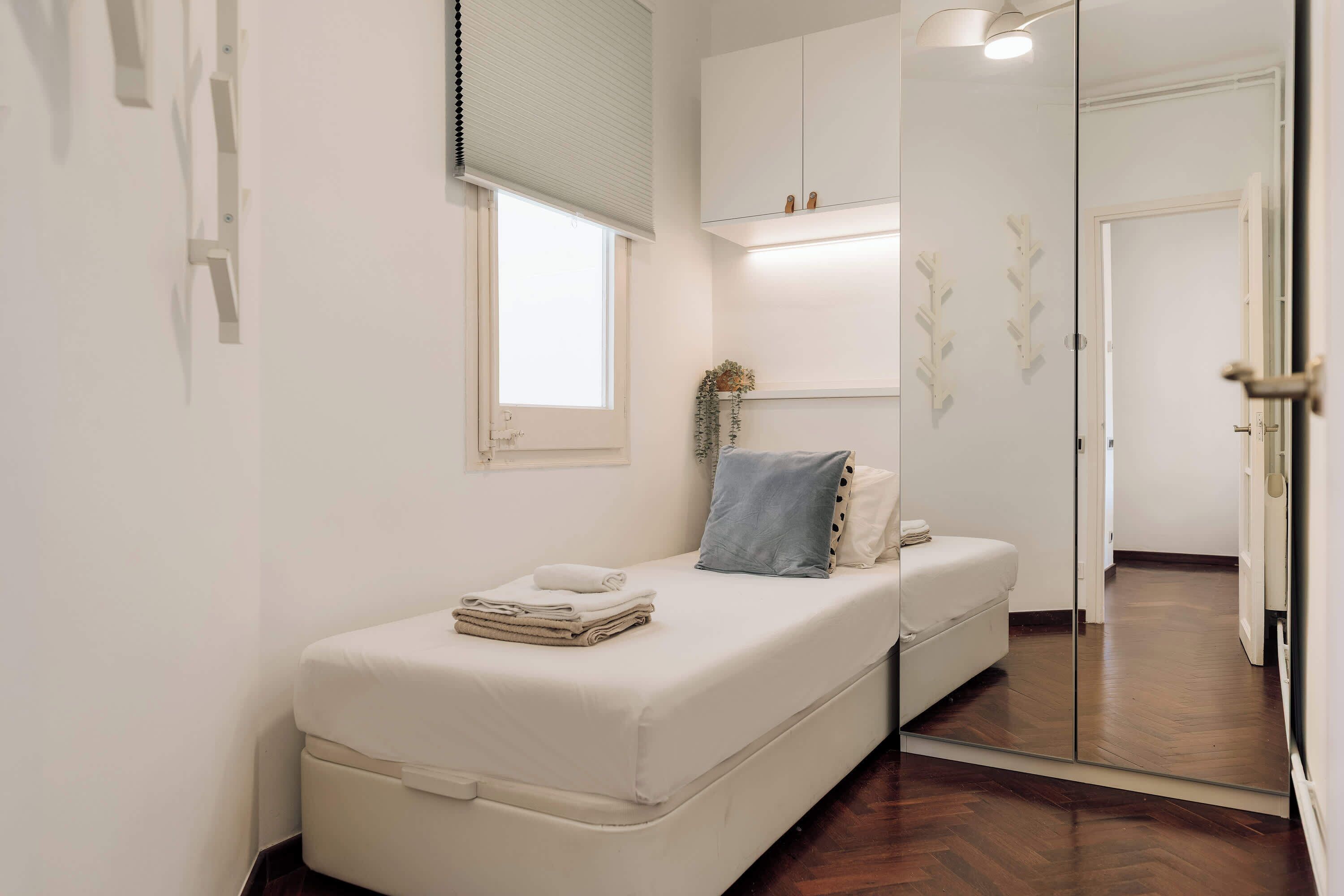 Une chambre à coucher avec un lit, une table de chevet, une fenêtre et un miroir.