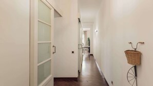 A hallway with a wooden floor, white walls, and a door with frosted glass panels. - Enjoy Apartments Paz - Bright apartment near Sagrada Familia (Barcelona)