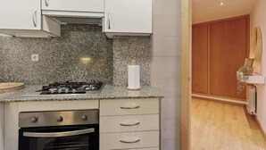 A kitchen with granite countertops, a gas stove, an oven, and a wooden cabinet. - Enjoy Apartments Paz 2 - Bright apartment near Sagrada Familia (Barcelona)