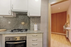 Una cocina con encimeras de granito, estufa a gas, horno y un armario de madera.