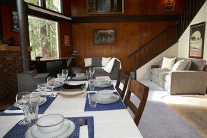 A dining area with a table set for four, a sofa, and a staircase. - Cinnamon Bear Cabin - Tranquil 2 bedroom cabin in welcoming Lake Cushman Area (Hoodsport)