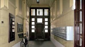 A hallway with a bicycle, a door with windows, and a wall-mounted radiator. - Lazienki park Bagatela street Top floor apartment with lift (Warszawa)