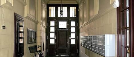 A hallway with a bicycle, a door with windows, and a wall-mounted radiator.