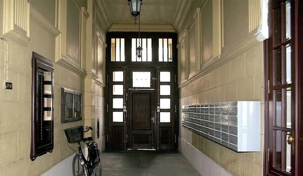 Um corredor com uma bicicleta, uma porta com janelas e um radiador fixado na parede.