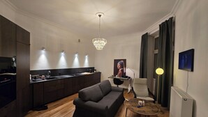 A modern living room with a dark sofa, a round coffee table, and a dining area with a kitchen counter. - Lazienki park Bagatela street Top floor apartment with lift (Warszawa)